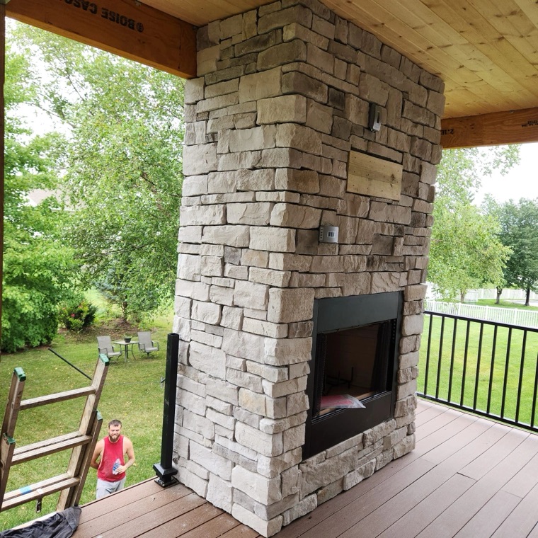 Stone outdoor fireplace built on a covered deck